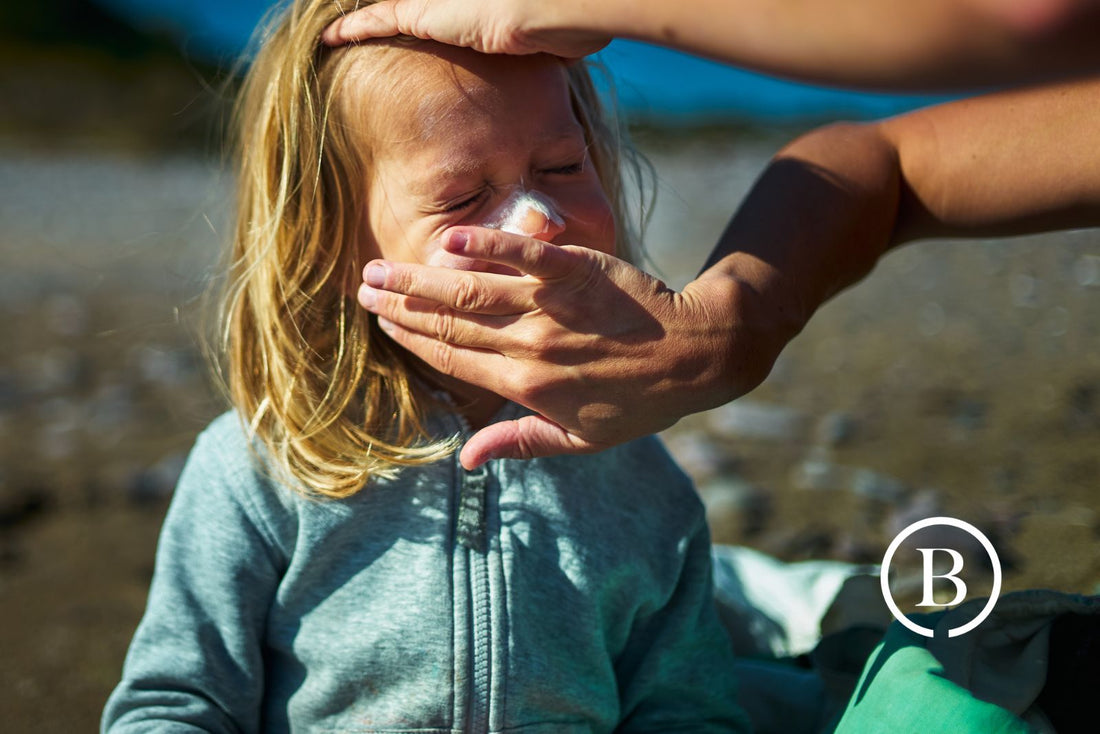 closeup of child getting sunscreen applied by adult hands