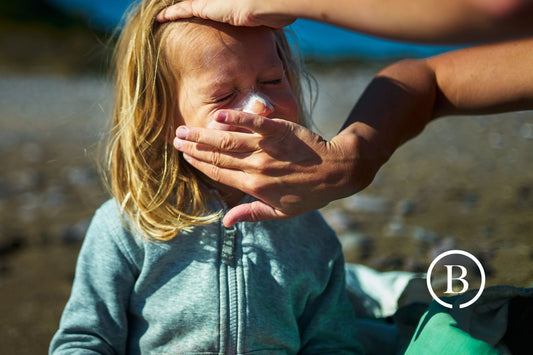 closeup of child getting sunscreen applied by adult hands