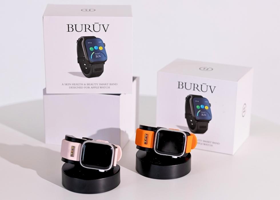 Two BURUV bands, boxes, and charging stations with Apple Watches on cream background