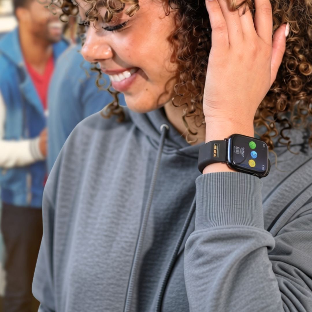 woman in grey hoodie wearing black BURŪV® band with Apple Watch® against blurred tailgate