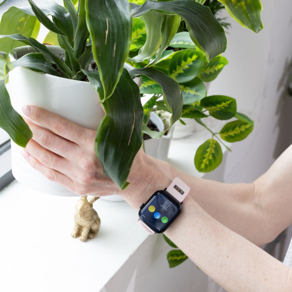 Person wearing a BURŪV watch band with a plant in the background