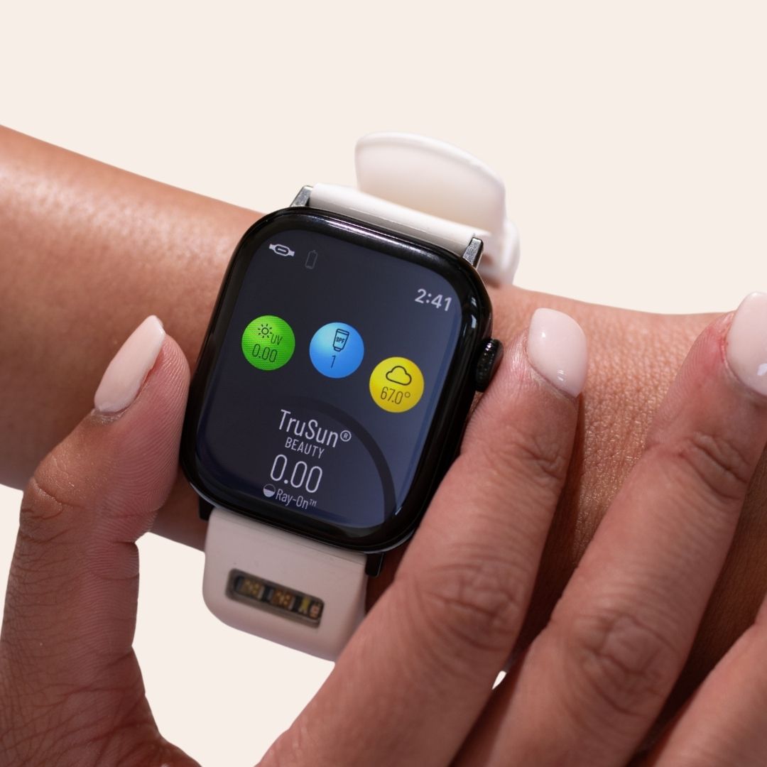 Woman's wrist wearing white BURŪV® smart band on app screen showing "TruSun®" score, UVI, SPF, and temperature on cream background